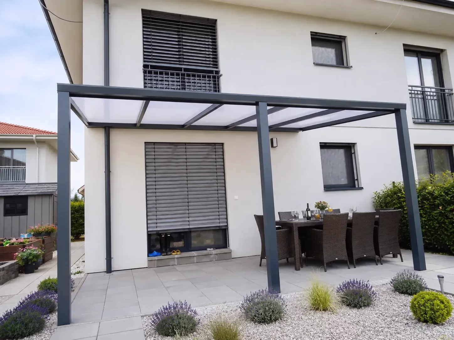 Antracitová hliníková pergola Basic Class nad terasou s jedálenským stolom pri rodinnom dome so záhradou levandule