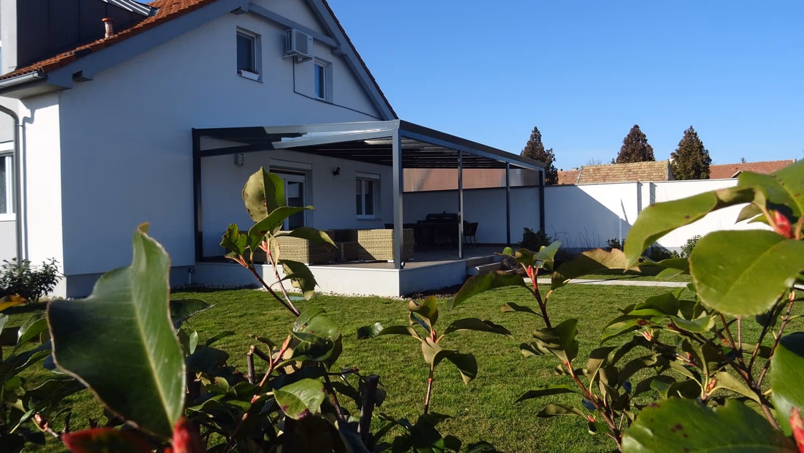 Hliníková pergola Economic Class pri dome so šikmou strechou a veľkým oknom