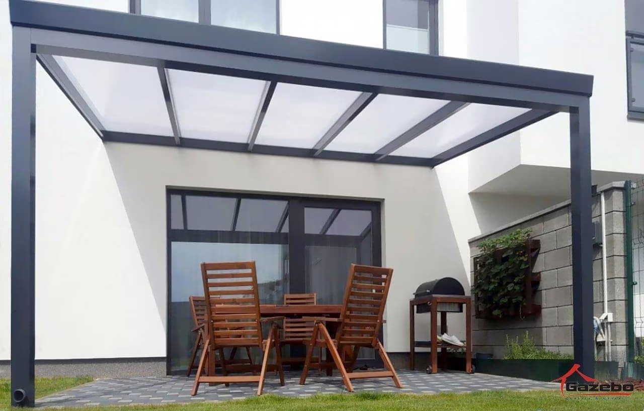 Antracitová hliníková pergola Economic Class pri bielom dome s dreveným stolom a stoličkami