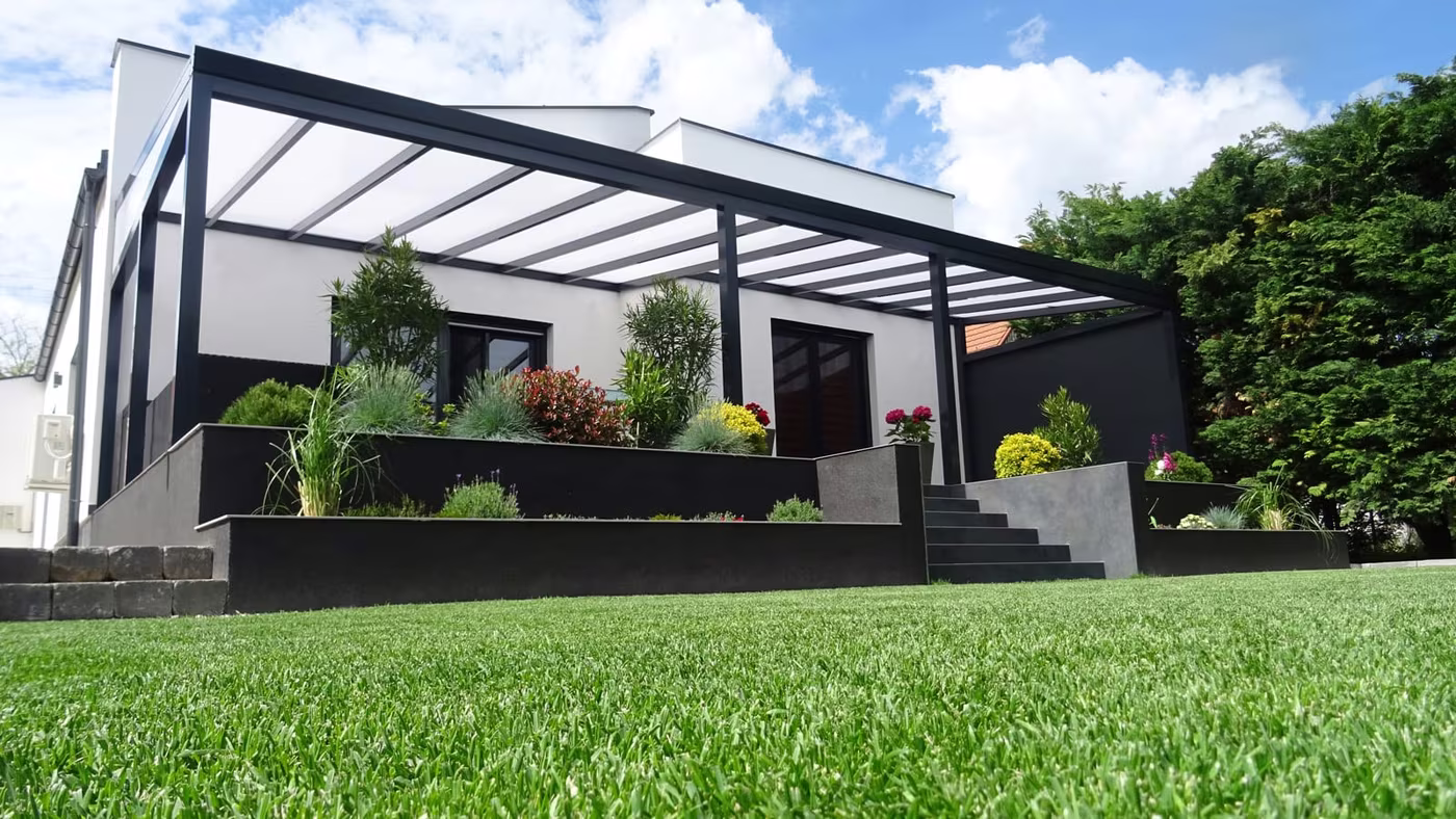 Antracitová hliníková pergola Economic Class nad terasou na svahovitom pozemku s trávnikom
