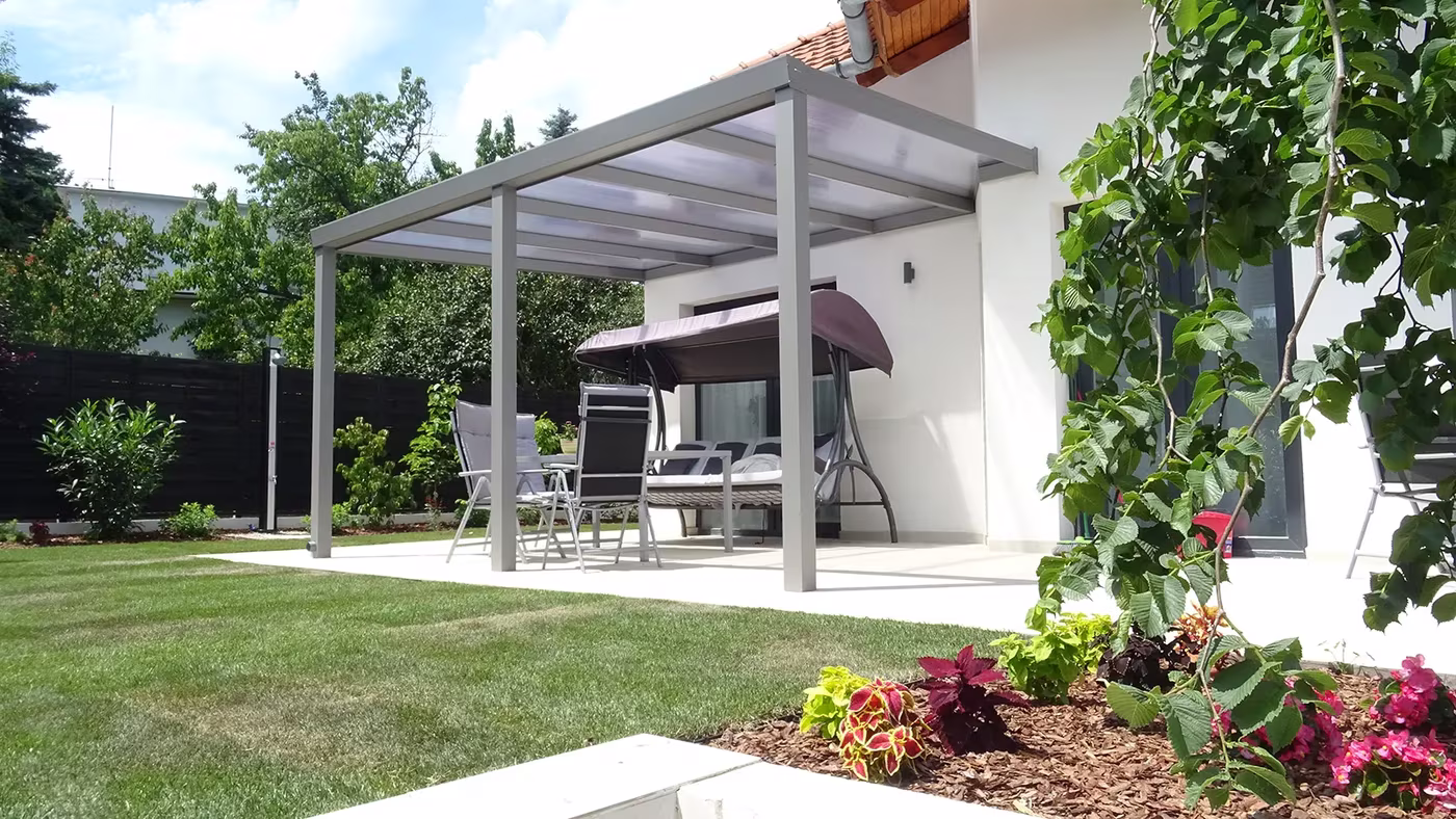 Antracitová hliníková pergola Economic Class nad dláždenou plochou medzi domami s posedením