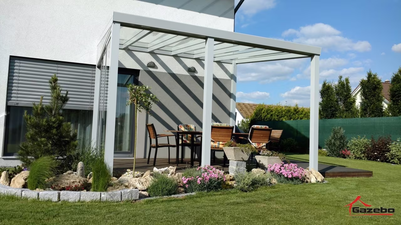 Biela hliníková pergola Top Class nad terasou s jedálenským posedením a upravenou záhradou