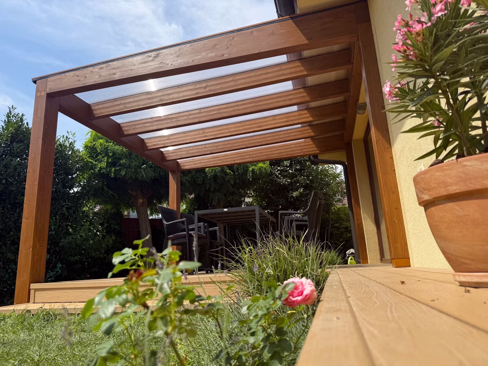 Drevená pergola Milano s priehľadnou polykarbonátovou strechou pri terase rodinného domu