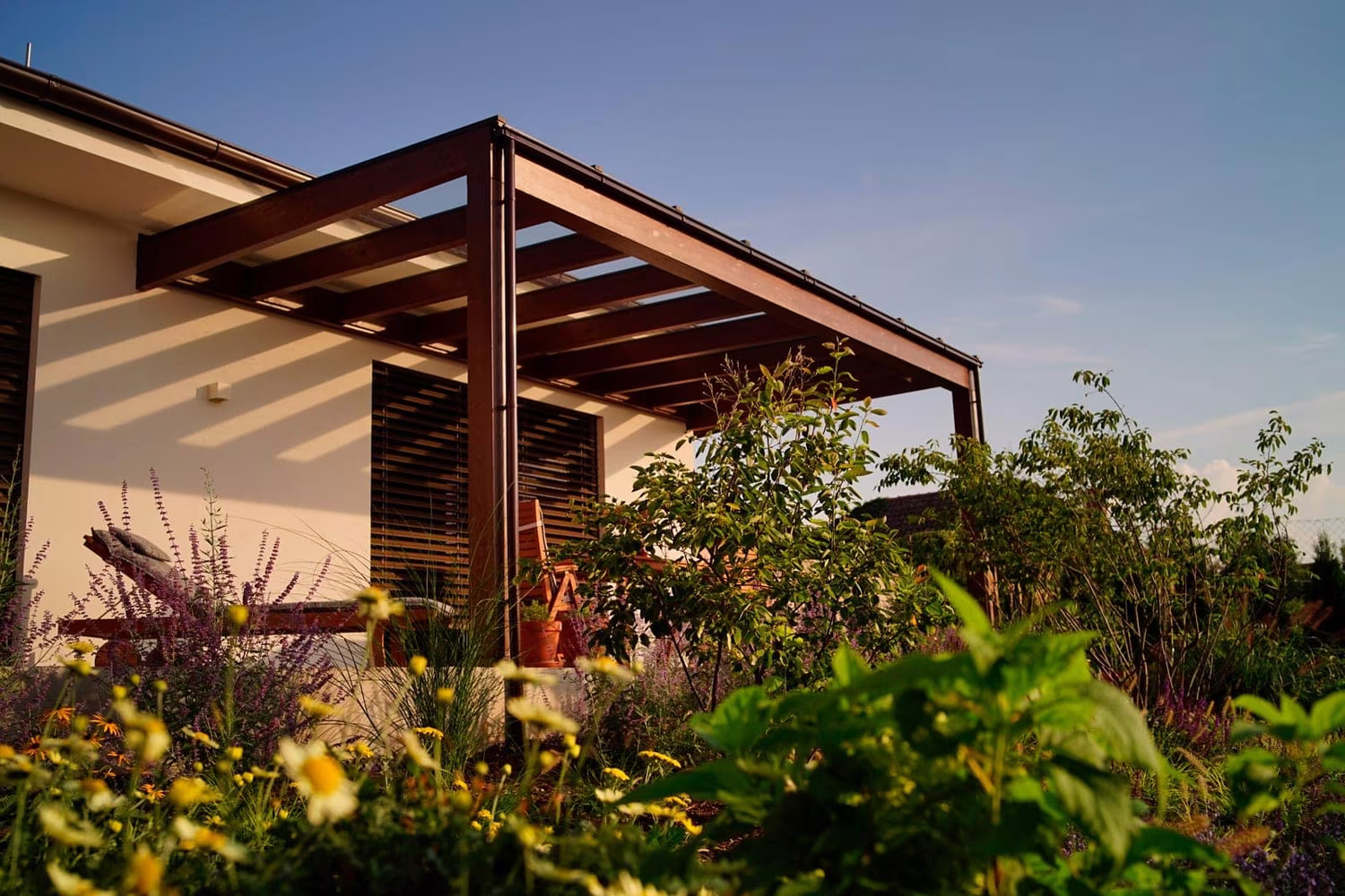 Drevená pergola Milano s bočnou drevenou výplňou a kvetinovou záhradou