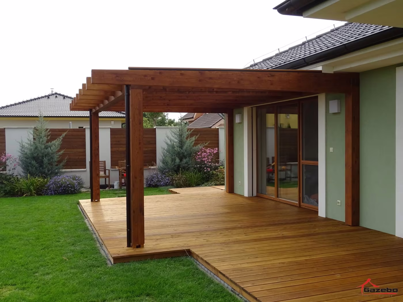 Drevená pergola Fénix nad vyvýšenou drevenou terasou pri rodinnom dome